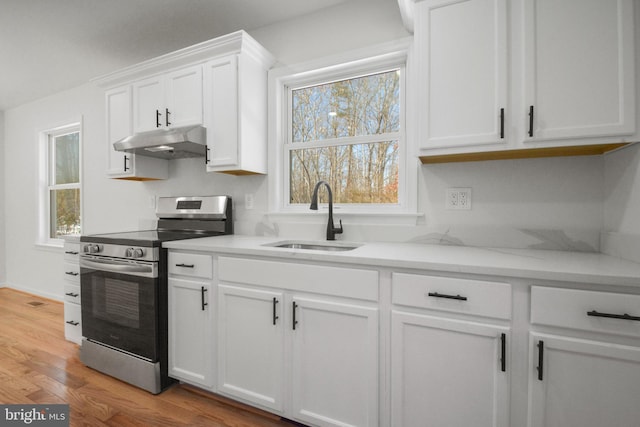 kitchen with sink, a healthy amount of sunlight, wood-type flooring, stainless steel electric stove, and white cabinets