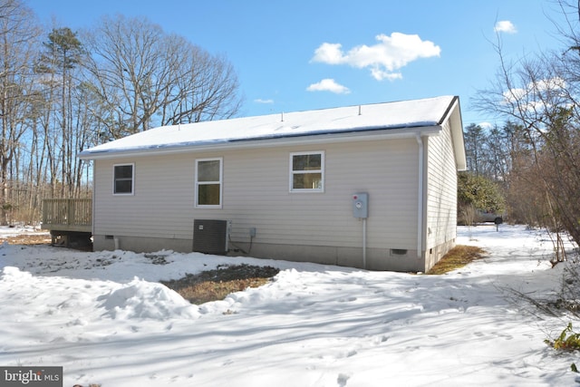 snow covered property with central air condition unit and a deck