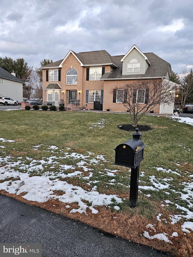 view of front of house featuring a shingled roof, brick siding, and a lawn