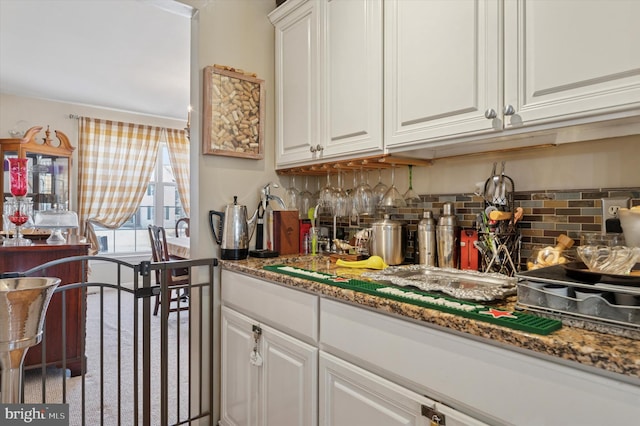 kitchen featuring stone counters, white cabinets, and decorative backsplash