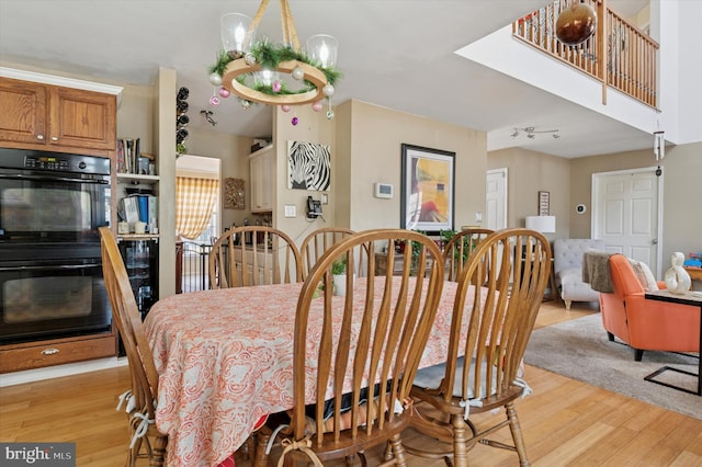 dining room with light wood-style floors, a chandelier, and rail lighting