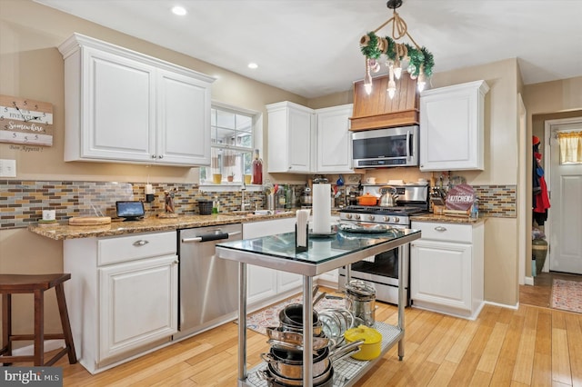 kitchen with light wood finished floors, appliances with stainless steel finishes, backsplash, and white cabinetry