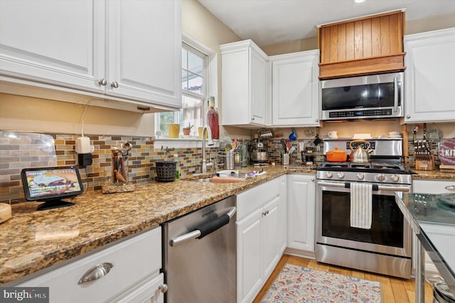 kitchen featuring light wood-type flooring, appliances with stainless steel finishes, white cabinets, and a sink