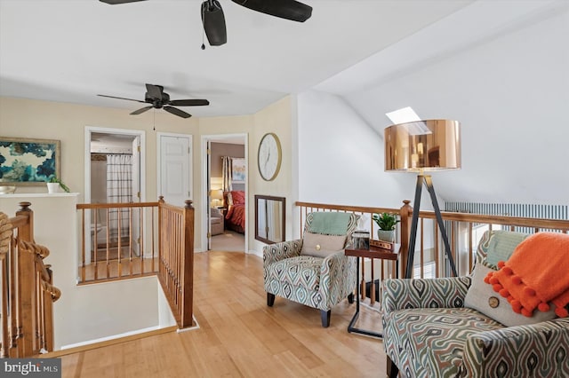 sitting room featuring ceiling fan, wood finished floors, and an upstairs landing