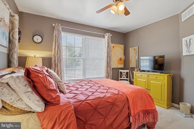 bedroom with light carpet, ceiling fan, visible vents, and baseboards