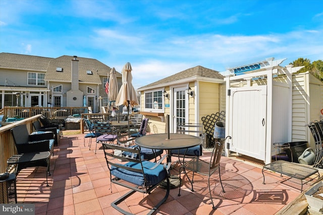 view of patio / terrace with outdoor dining area, a pergola, and an outbuilding