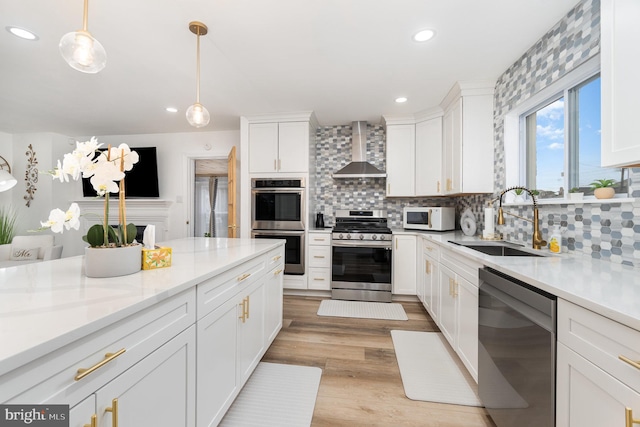 kitchen featuring appliances with stainless steel finishes, hanging light fixtures, decorative backsplash, white cabinets, and wall chimney exhaust hood