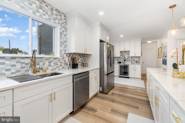 kitchen featuring white cabinetry, sink, pendant lighting, backsplash, and stainless steel appliances