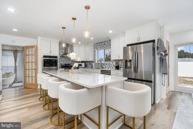 kitchen with decorative light fixtures, white cabinets, backsplash, a kitchen island, and stainless steel appliances