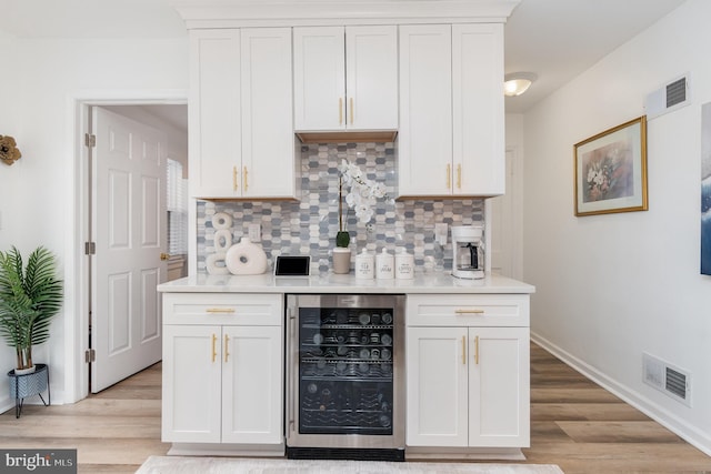 kitchen featuring white cabinets, tasteful backsplash, beverage cooler, and light hardwood / wood-style floors