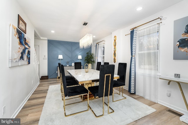 dining space with light wood-type flooring and a chandelier