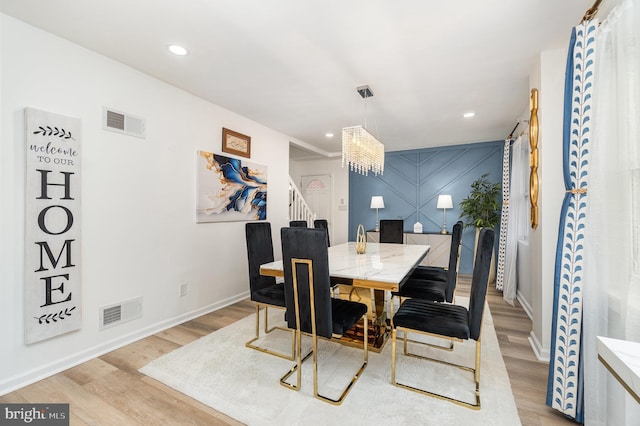 dining room with light hardwood / wood-style flooring and a notable chandelier