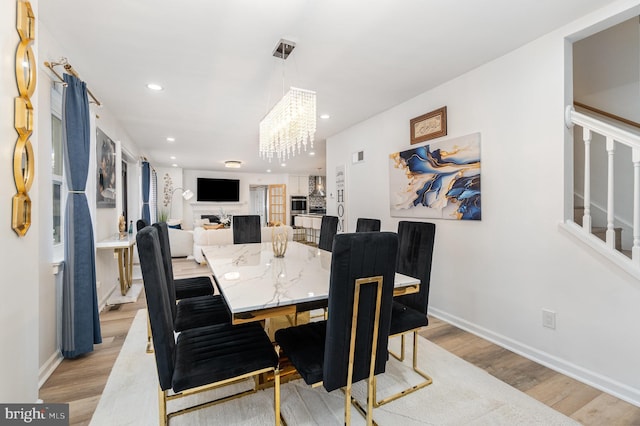 dining space with a notable chandelier and light hardwood / wood-style flooring