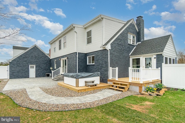 back of house with a patio, a deck, a lawn, and a hot tub