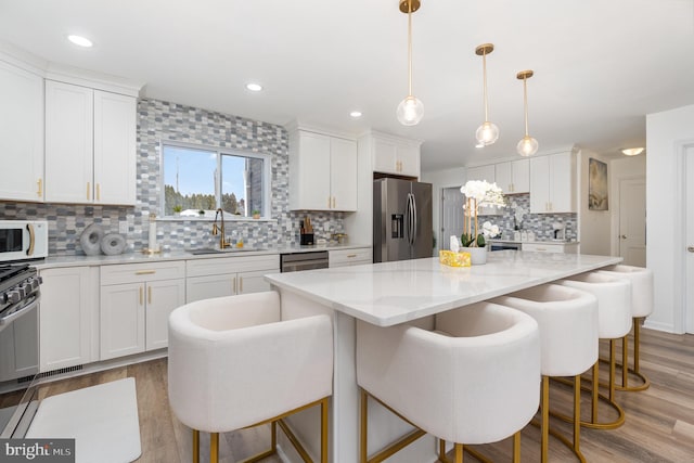 kitchen featuring sink, pendant lighting, appliances with stainless steel finishes, and a kitchen island