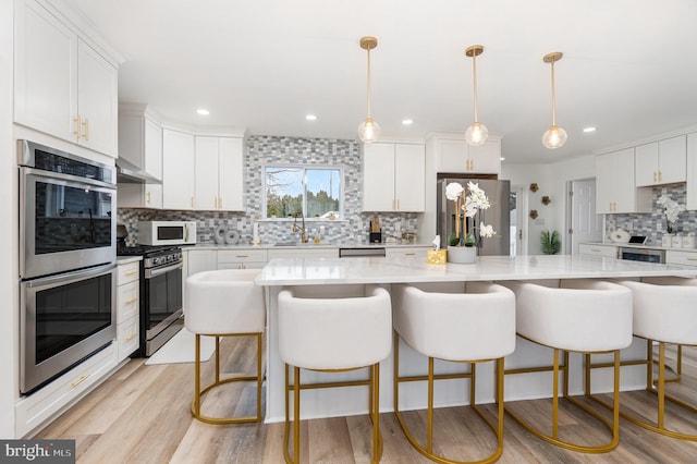 kitchen with decorative light fixtures, white cabinets, and appliances with stainless steel finishes