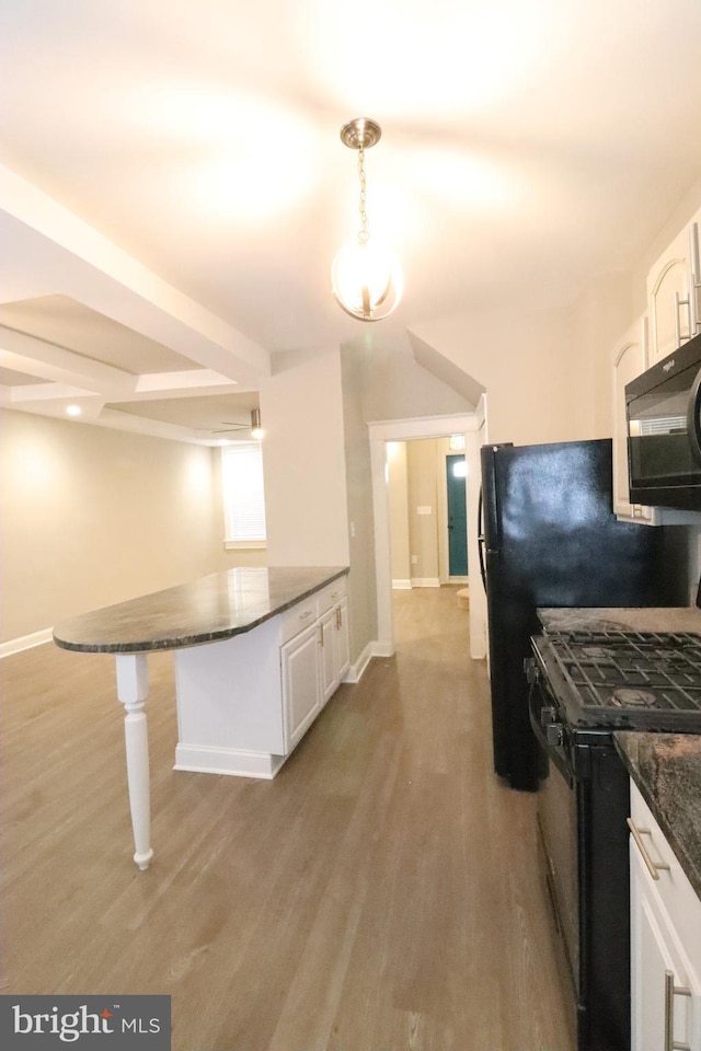 kitchen with a kitchen bar, white cabinetry, hanging light fixtures, light hardwood / wood-style floors, and black appliances