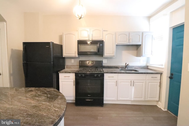 kitchen with sink, dark wood-type flooring, white cabinetry, black appliances, and dark stone counters