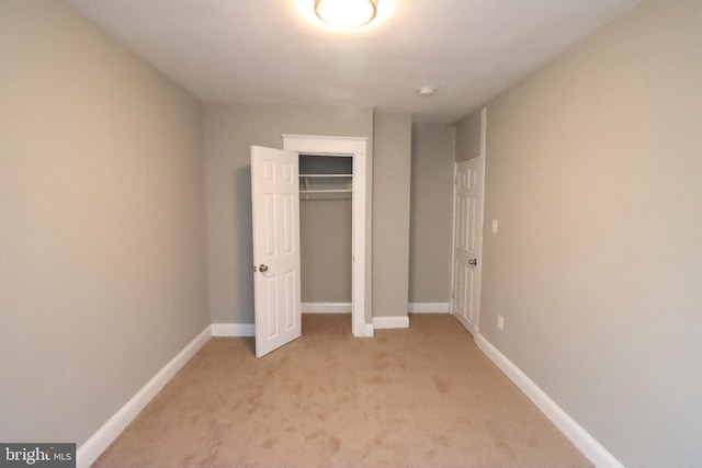 unfurnished bedroom with light carpet and a closet