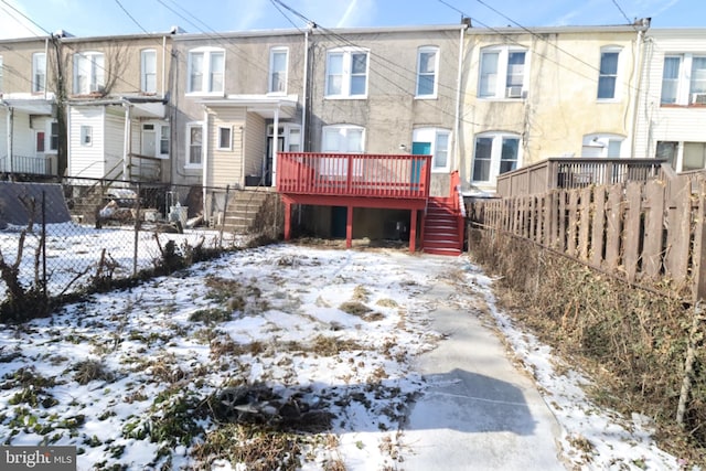 snow covered back of property featuring a wooden deck