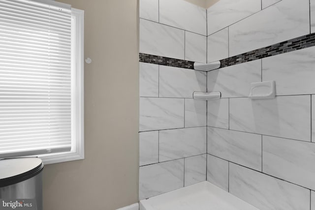 bathroom featuring a tile shower and a healthy amount of sunlight