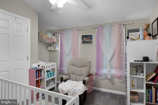 carpeted bedroom with ceiling fan and a nursery area