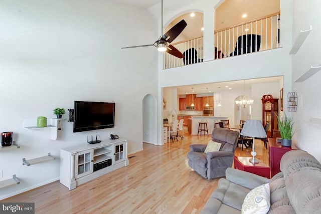 living room featuring ceiling fan with notable chandelier and light hardwood / wood-style flooring