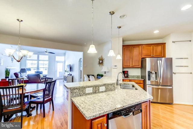 kitchen with appliances with stainless steel finishes, decorative light fixtures, sink, and light wood-type flooring