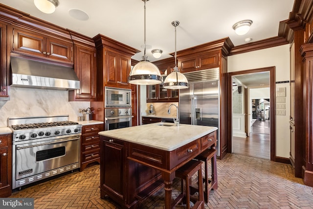 kitchen with under cabinet range hood, appliances with stainless steel finishes, light countertops, and a sink