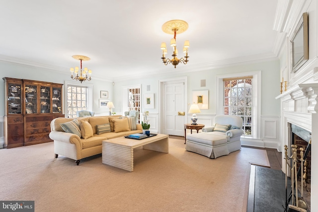 carpeted living area featuring a wainscoted wall, crown molding, a decorative wall, a premium fireplace, and a chandelier