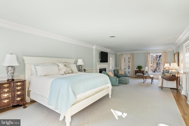 bedroom with ornamental molding, a fireplace, and wood finished floors