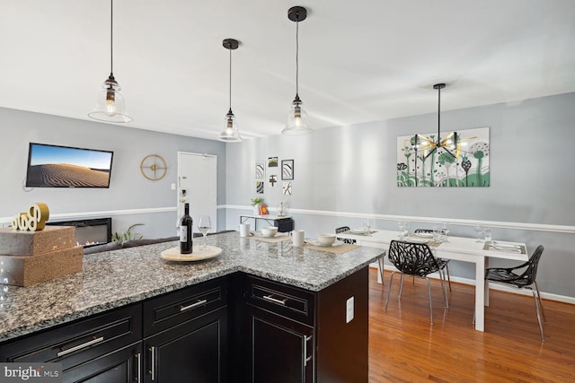 kitchen featuring light stone counters, hardwood / wood-style floors, hanging light fixtures, and an inviting chandelier