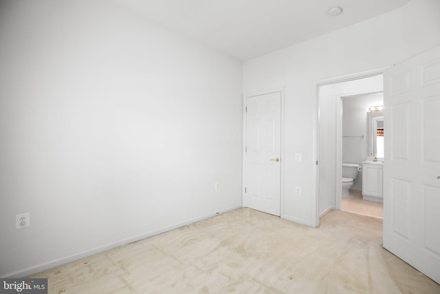 unfurnished bedroom featuring light carpet and connected bathroom