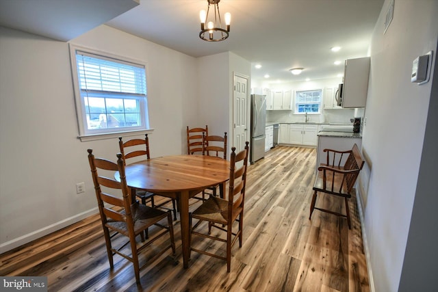 dining area with sink, a notable chandelier, and light hardwood / wood-style flooring