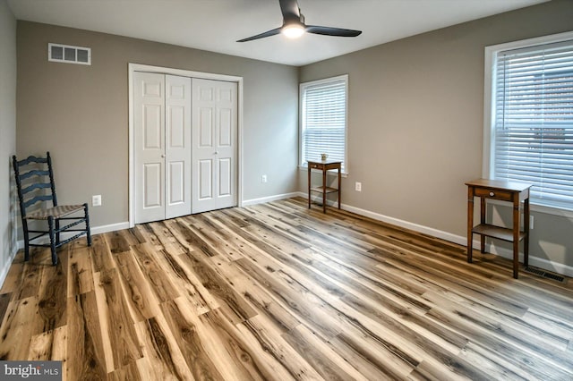 unfurnished bedroom with hardwood / wood-style flooring, ceiling fan, and a closet