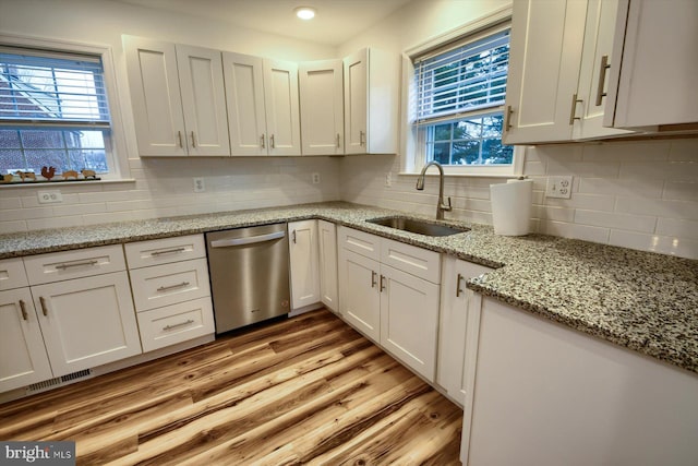 kitchen featuring white cabinetry, dishwasher, sink, light stone countertops, and light wood-type flooring