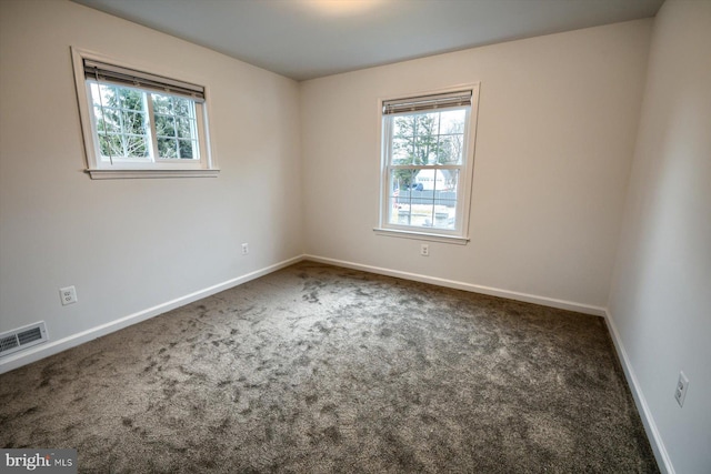 spare room with a healthy amount of sunlight and dark colored carpet