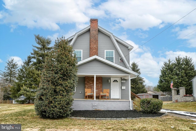 view of front of property with a storage shed, a front yard, and covered porch