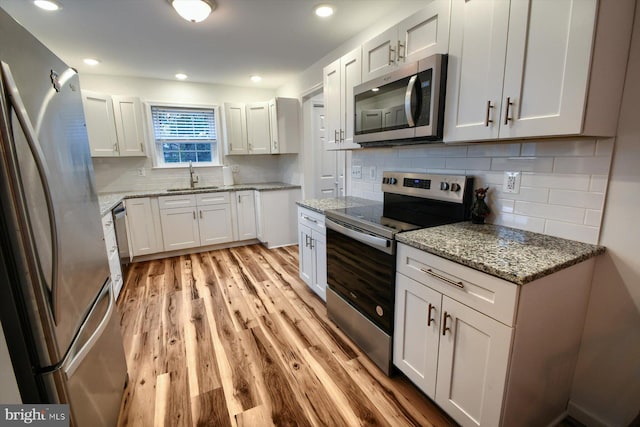 kitchen with white cabinetry, appliances with stainless steel finishes, sink, and light wood-type flooring