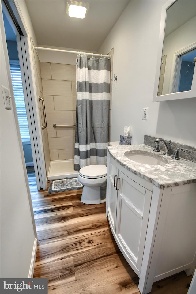 bathroom featuring walk in shower, vanity, toilet, and hardwood / wood-style floors