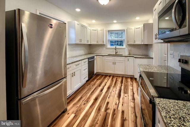 kitchen featuring sink, white cabinets, decorative backsplash, stainless steel appliances, and light hardwood / wood-style flooring