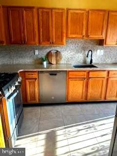 kitchen with appliances with stainless steel finishes, backsplash, light tile patterned floors, and sink