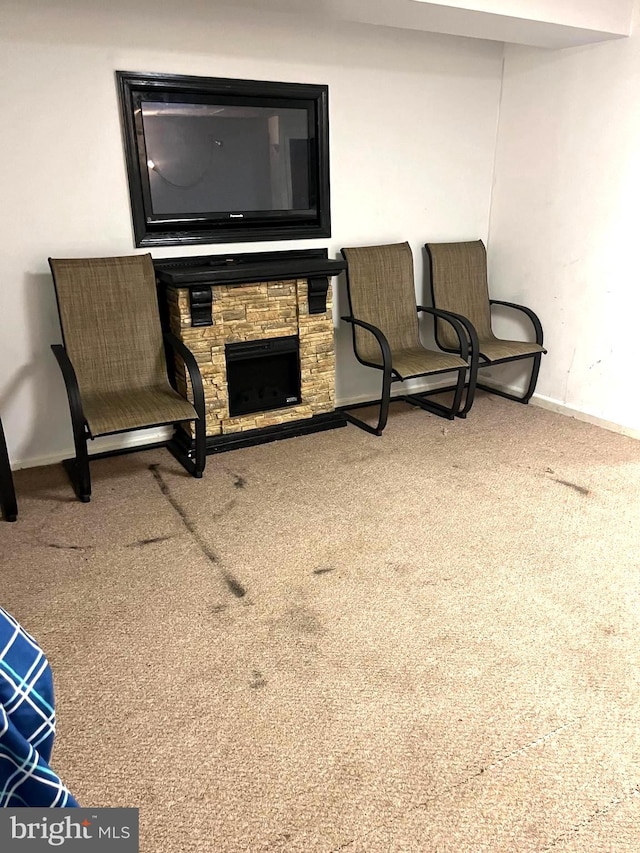 living area featuring carpet flooring and a stone fireplace