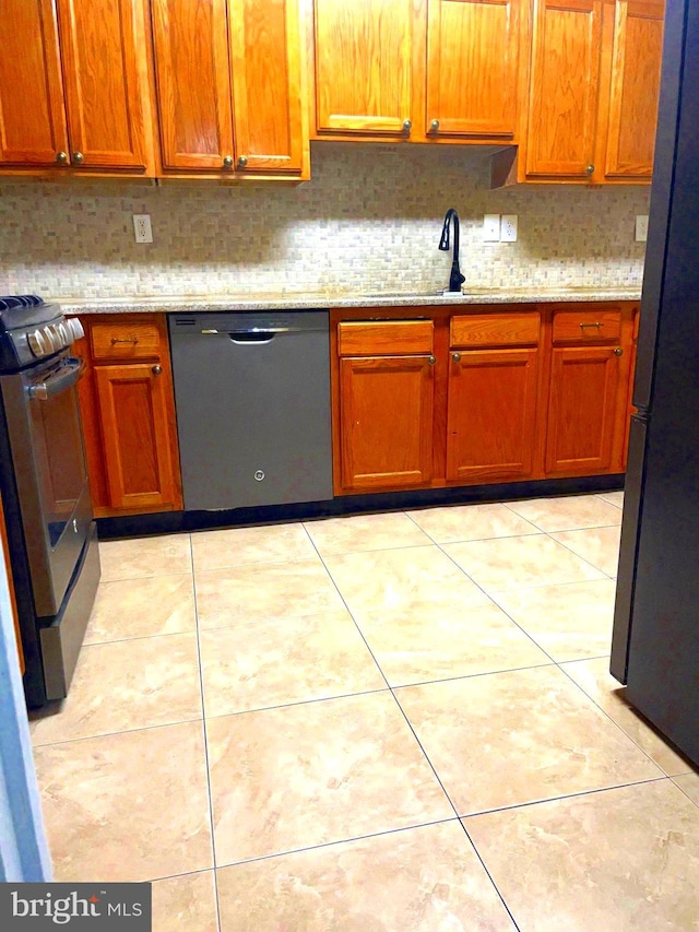 kitchen with light stone countertops, sink, backsplash, light tile patterned floors, and appliances with stainless steel finishes