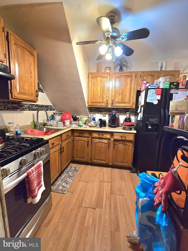 kitchen featuring ceiling fan, sink, black fridge, light wood-type flooring, and gas range