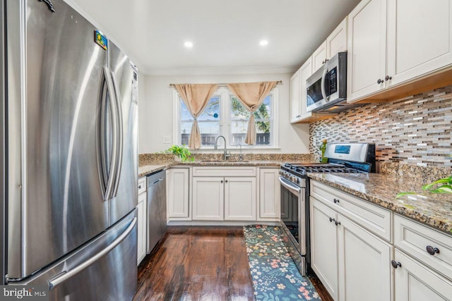 kitchen with light stone countertops, dark wood-type flooring, white cabinetry, stainless steel appliances, and sink