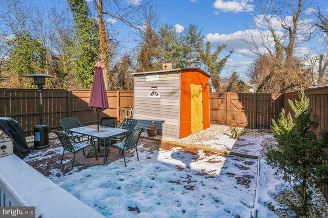 snow covered patio with a storage shed