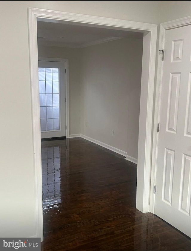 unfurnished room featuring dark wood-type flooring and ornamental molding