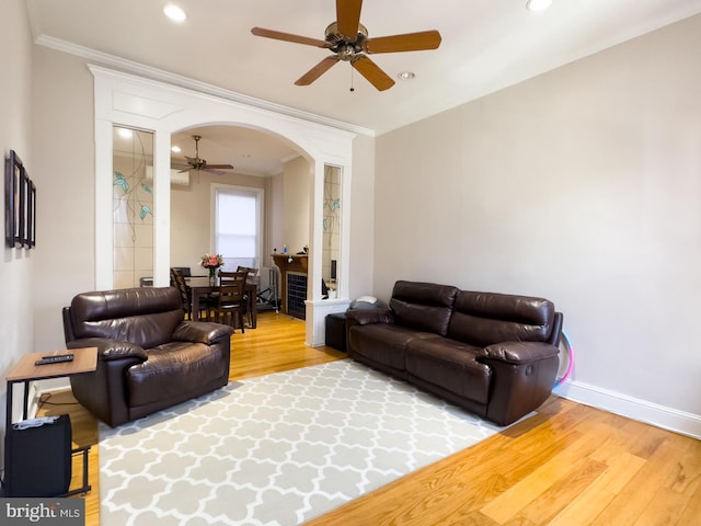 living room with ceiling fan, wood-type flooring, and ornamental molding