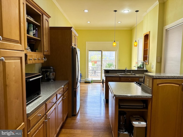 kitchen with stainless steel fridge, a kitchen island, crown molding, and sink